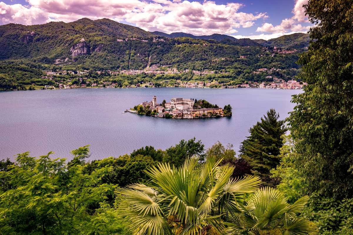 Vista panoramica di un lago alpino circondato da montagne e vegetazione lussureggiante.
