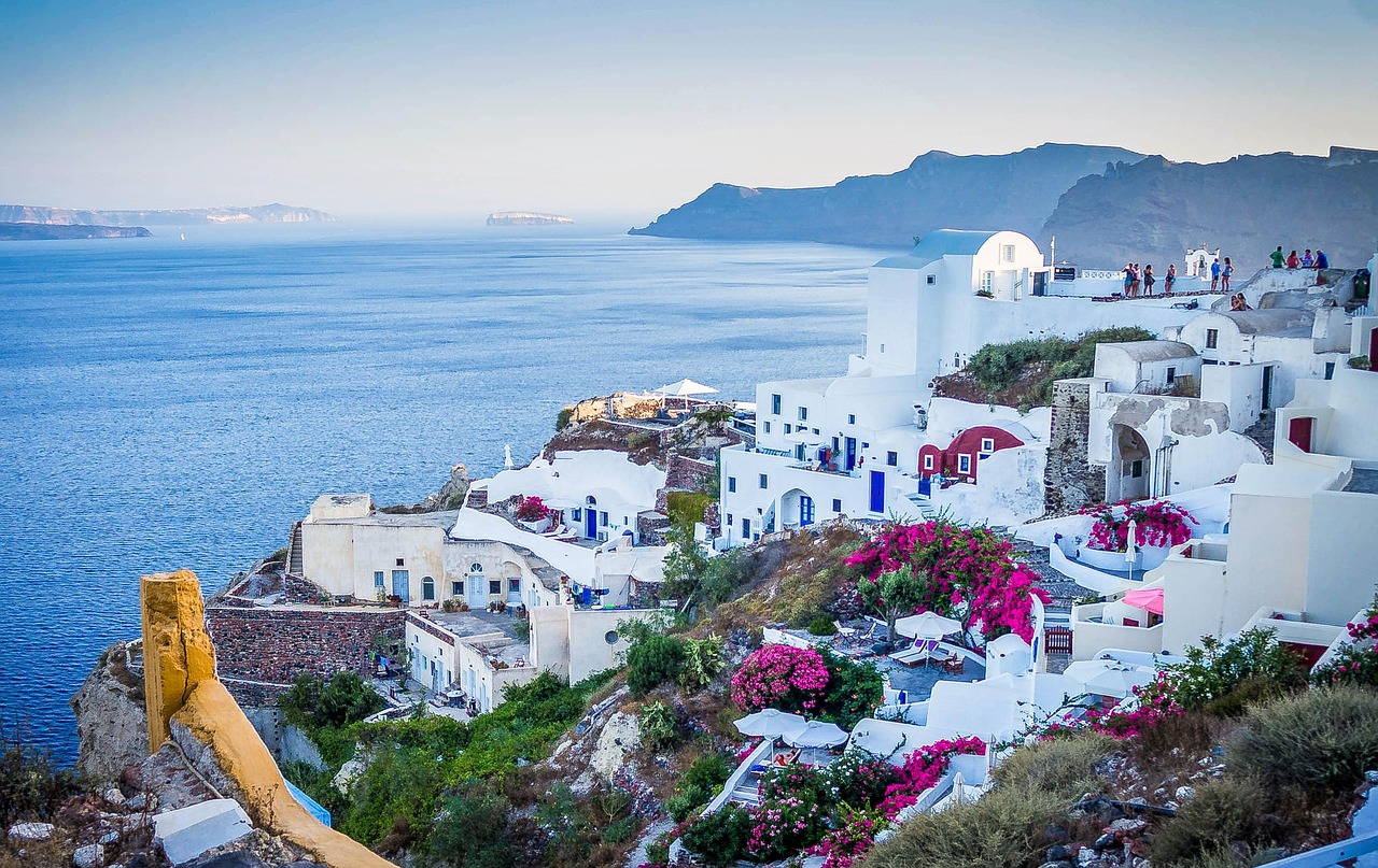 Panorama di un'isola greca con mare cristallino e case bianche, alternativa economica a Santorini.