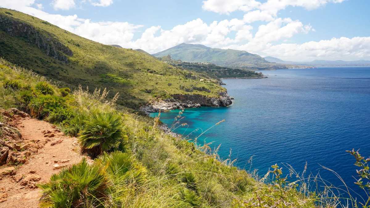 Caletta siciliana con acque turchesi e sabbia bianca, simile a luoghi esotici come la Thailandia.