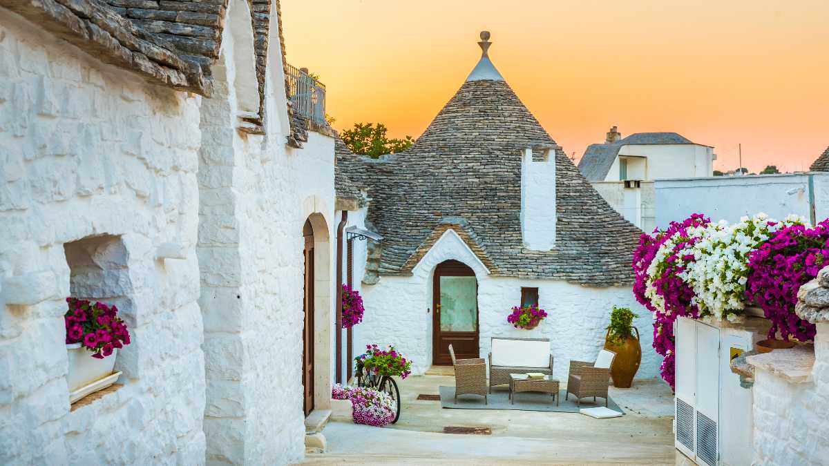 Trullo tradizionale pugliese circondato da ulivi in un paesaggio italiano.