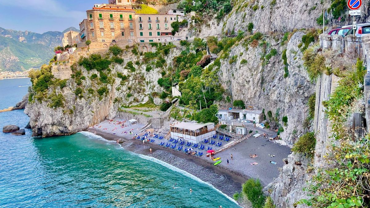 Spiaggia di Furore con il ponte che sovrasta i bagnanti e il mare cristallino sottostante.